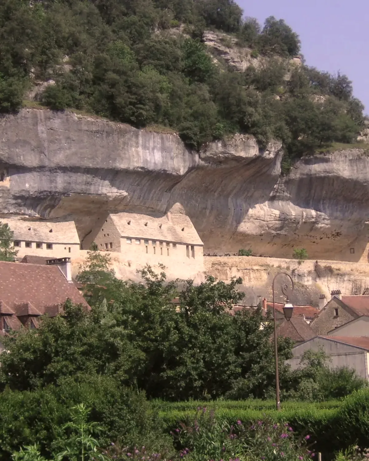 Le bourg des Eyzies serré sous le surplomb de la falaise calcaire.